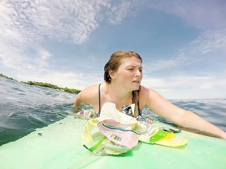 Le immagini sconvolgenti della surfista che cerca di nuotare circondata dalla plastica