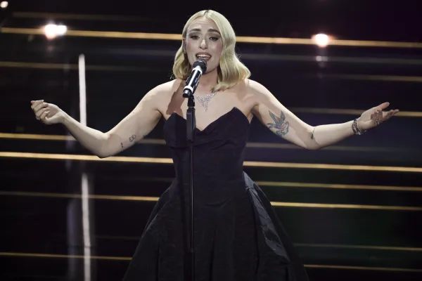 Mara Sattei: un outfit elegante con un tocco di stravaganza con un colore nero vibrante , capelli con un onda dolce e colore biondo sabbia eccellente trucco delicato che mette in evidenza il viso.  Franca Falezza Al Pacino