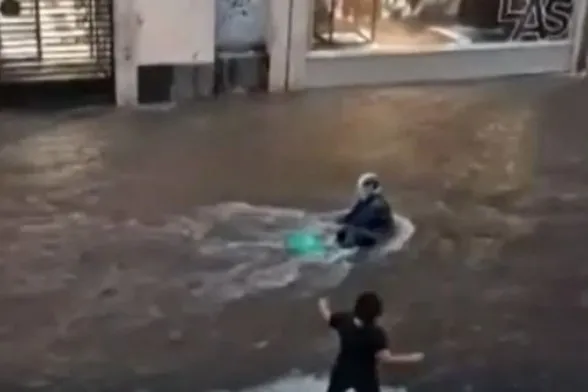 Frame tratto dal video che mostra una donna salvare un motociclista durante un alluvione mentre gli altri si limitavano a guardare 